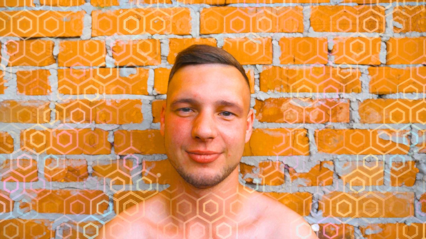 A man in front of a brick wall: geometry grows over the bricks while a clean circle keeps his face clear